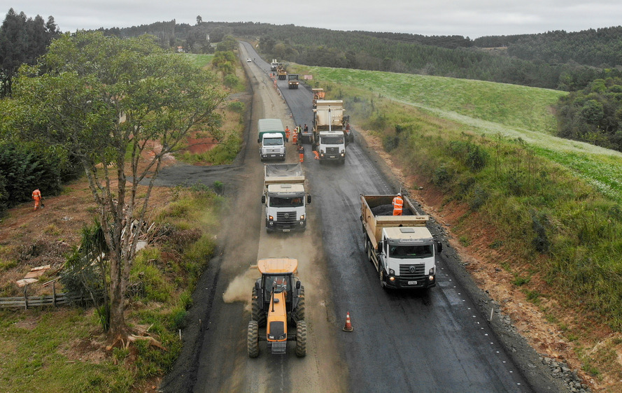Camnhões e tratores asfaltando estrada no paraná