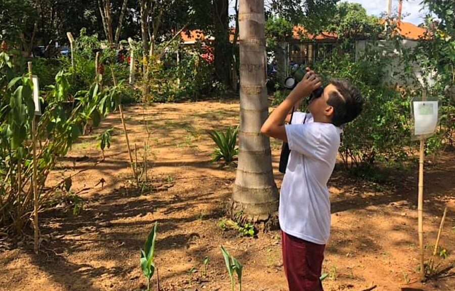 Samuel usando um binóculos em um jardim