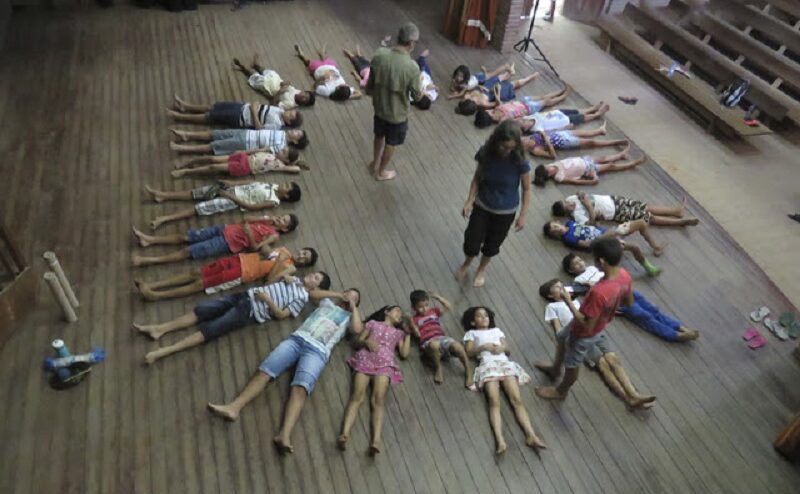 Crianças deitadas em roda no chão