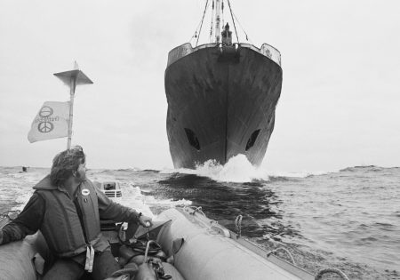 Ativista do Greenpeace pilotando bote na frente de navio baleeiro