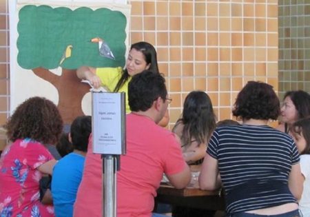 Educadora ambiental falando para pessoas em uma mesa