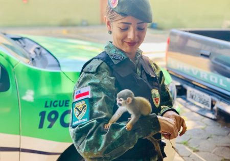 Mulher policial com pequeno macaco em seu braço