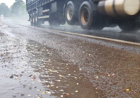 Foto de detalhe de caminhão passando perto de poça de água em dia com chuva